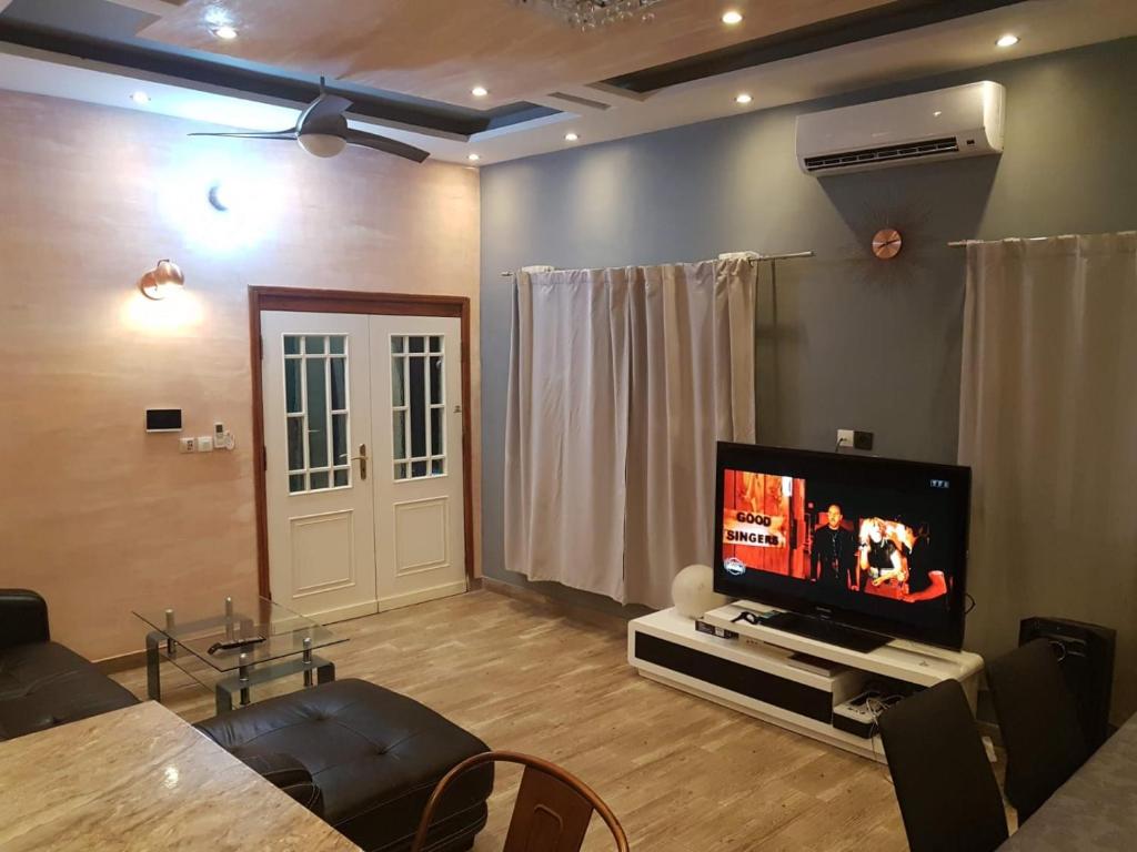 a living room with a flat screen tv and a table at Superbe appartement en résidence in Cotonou