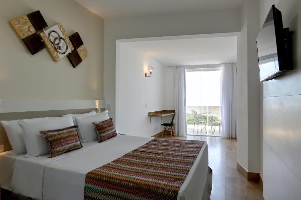 una camera da letto con un grande letto bianco e una finestra di Transamerica Fit Vitória Praia de Camburi a Vitória