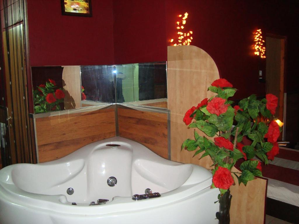 La salle de bains est pourvue d'un lavabo blanc et d'un vase avec des fleurs rouges. dans l'établissement vacation house יחידת אירוח פרטית הוד השרון, à Hod HaSharon