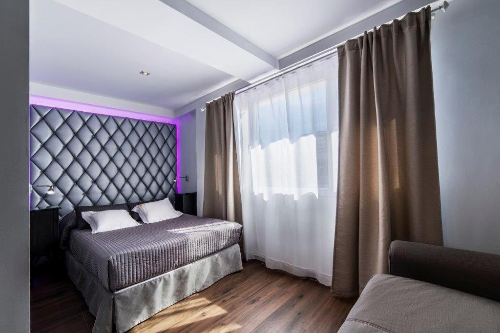 a bedroom with two beds and a window with purple lighting at Essence Hotel Boutique in Torremolinos