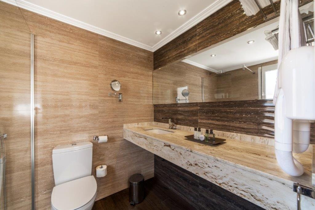 a bathroom with a toilet and a sink and a mirror at Essence Hotel Boutique in Torremolinos