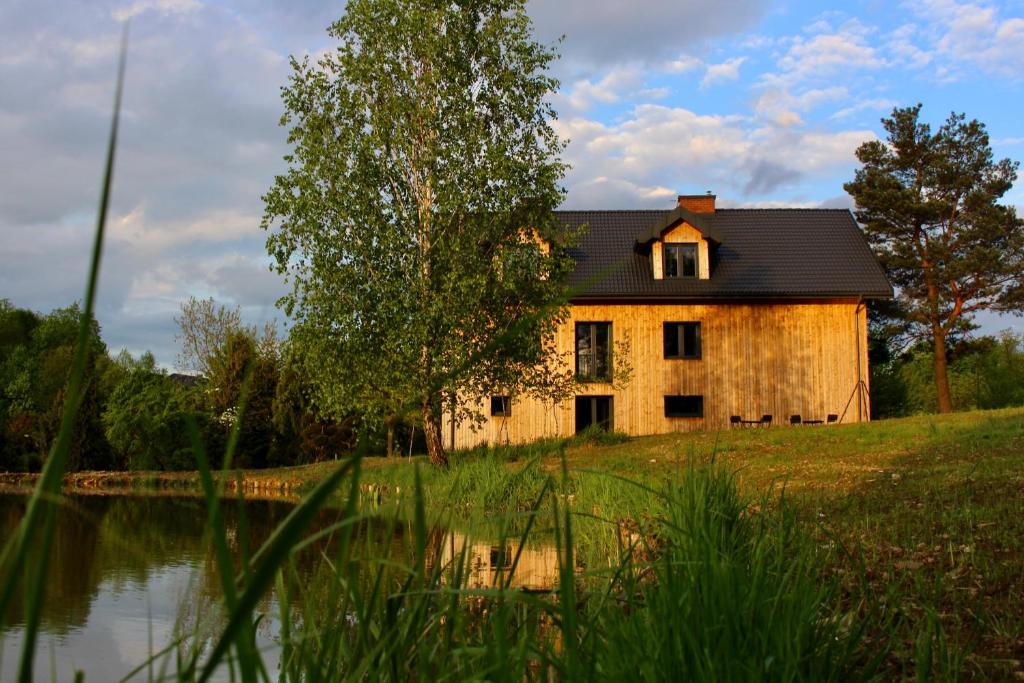 an old house sitting on a hill next to a lake at Garden Loft in Roczyny