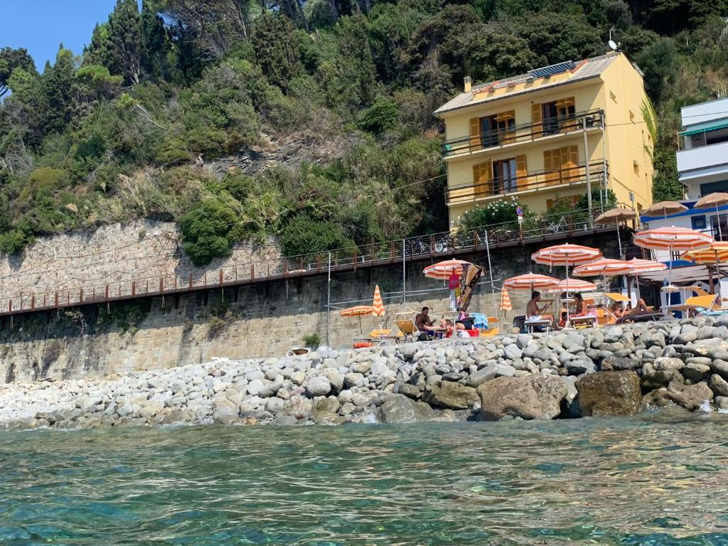 a beach with umbrellas and people sitting on the rocks at M'illumino d'immenso - MONEGLIA APARTMENTS in Moneglia