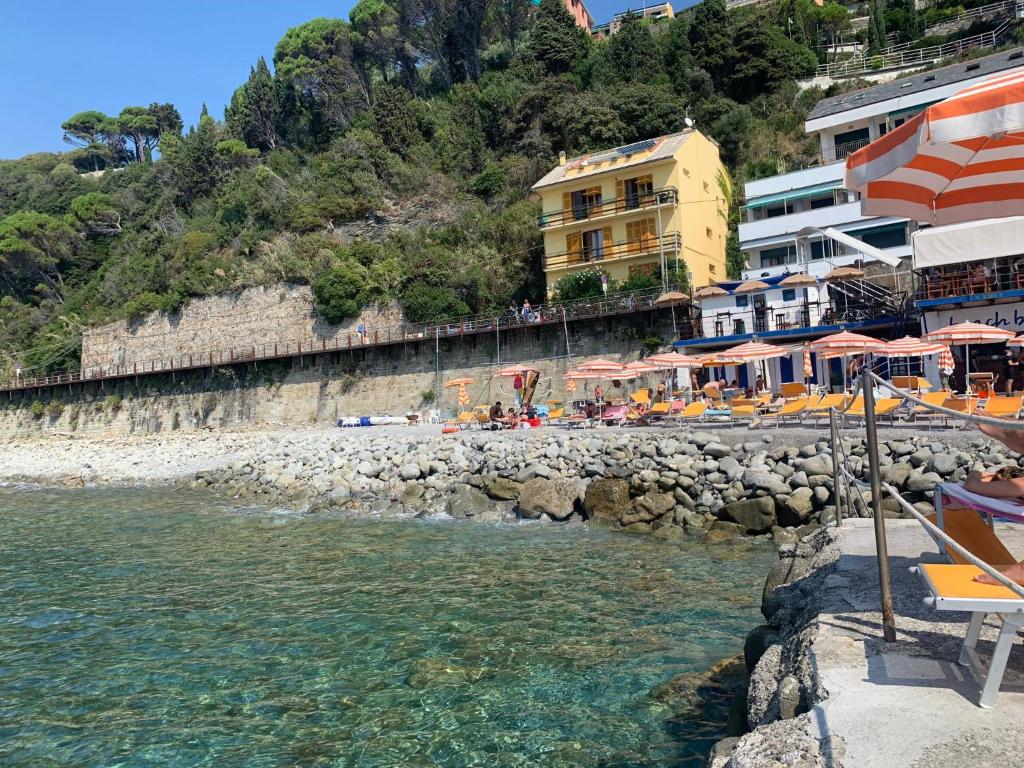 una playa con sillas y sombrillas junto al agua en M illumino d immenso - Un risveglio in mare MONEGLIA APARTMENTS en Moneglia