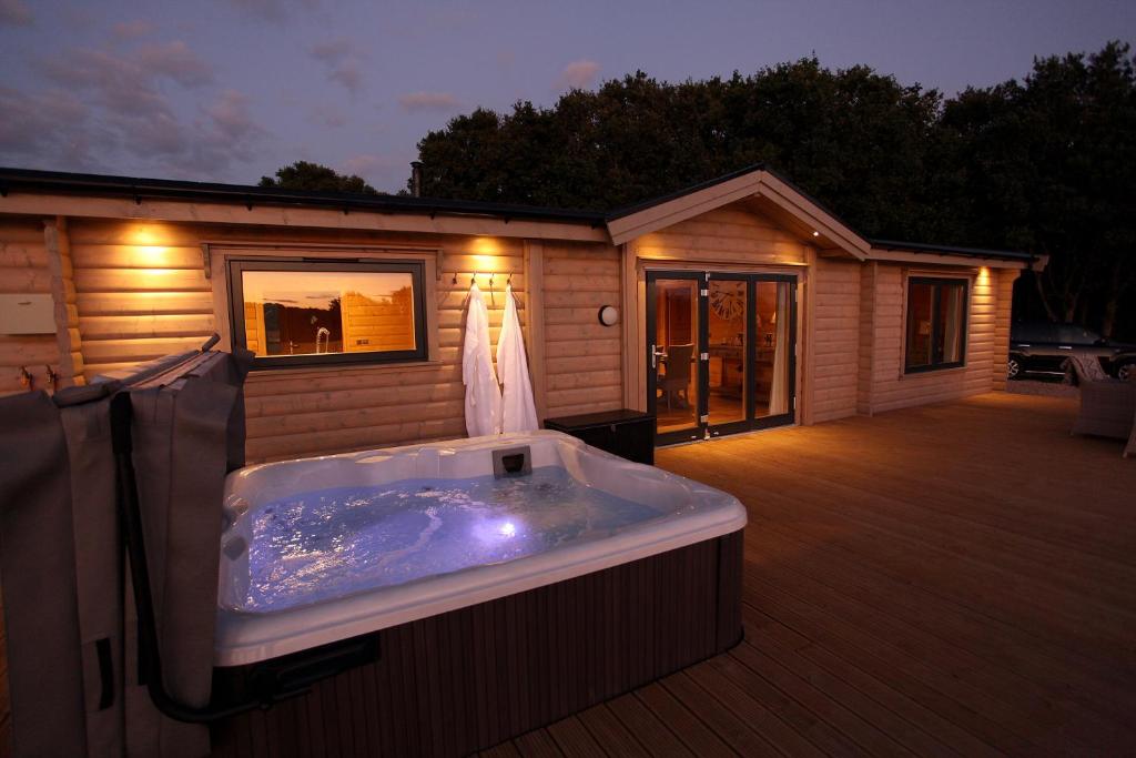 a hot tub on a deck next to a house at Cambridgeshire Lakes - luxury lodges in a stunning lake location in Gamlingay