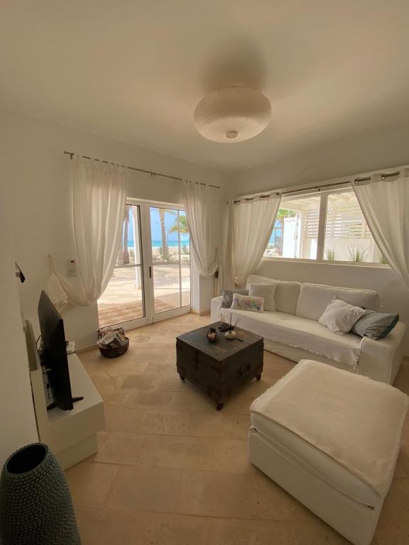 a living room with a white couch and a tv at Villa Nº 25 Alfredo Marchetti Suites on the Beach,Praia de Chaves BV in Cabeçadas