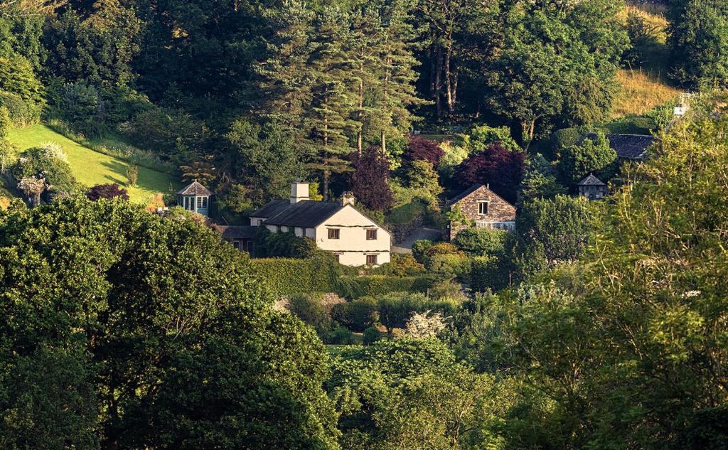 uma casa no meio de uma colina com árvores em Townfoot Byre, Troutbeck - E.V friendly em Windermere