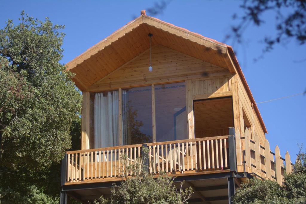 a tree house with a large window and a balcony at Ajloun Wooden Huts اكواخ عجلون الخشبية Live amid nature in Umm al Manābī‘
