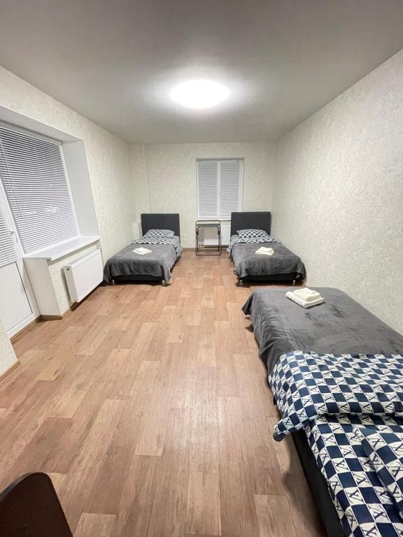 a room with three beds and a wooden floor at Апартаменты Проспект Победы 101 in Chernihiv