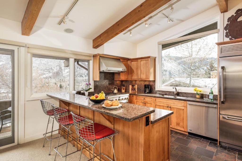 una cocina con armarios de madera y una gran isla con taburetes. en Deluxe 4 Bedroom - Aspen Alps #507-8, en Aspen