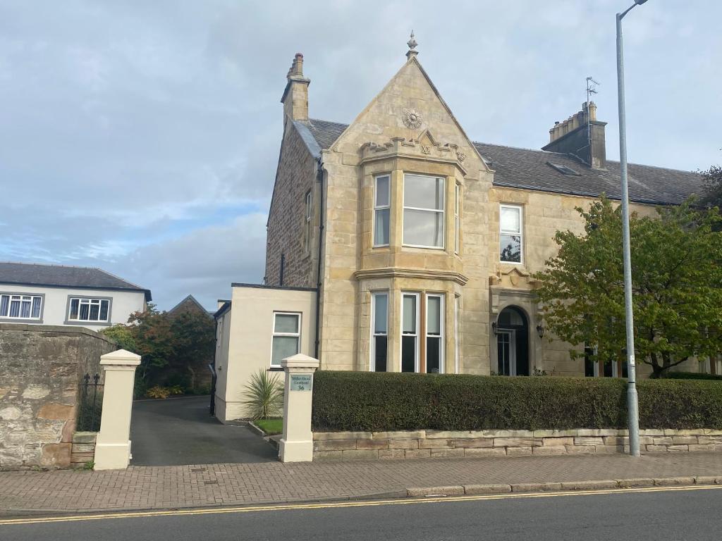 ein altes Steinhaus mit einem Tor davor in der Unterkunft Miller House Courtyard in Ayr