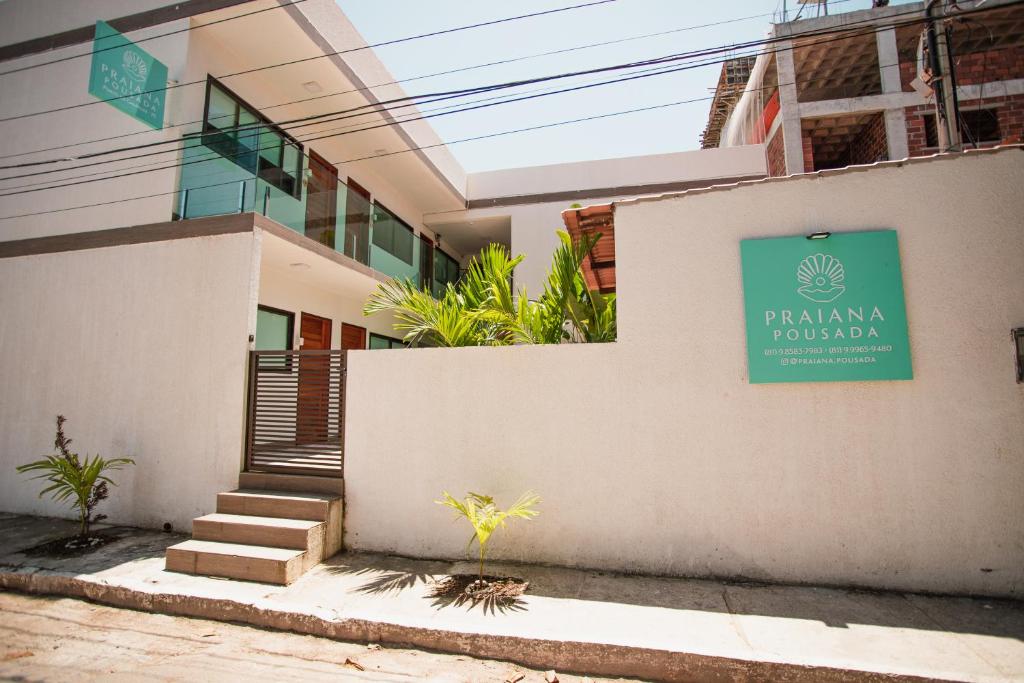 a building with a green sign on the side of it at Pousada Praiana in Porto De Galinhas