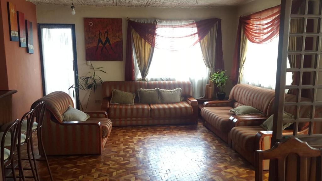 a living room with two leather couches and two windows at La Muralla in Cuenca