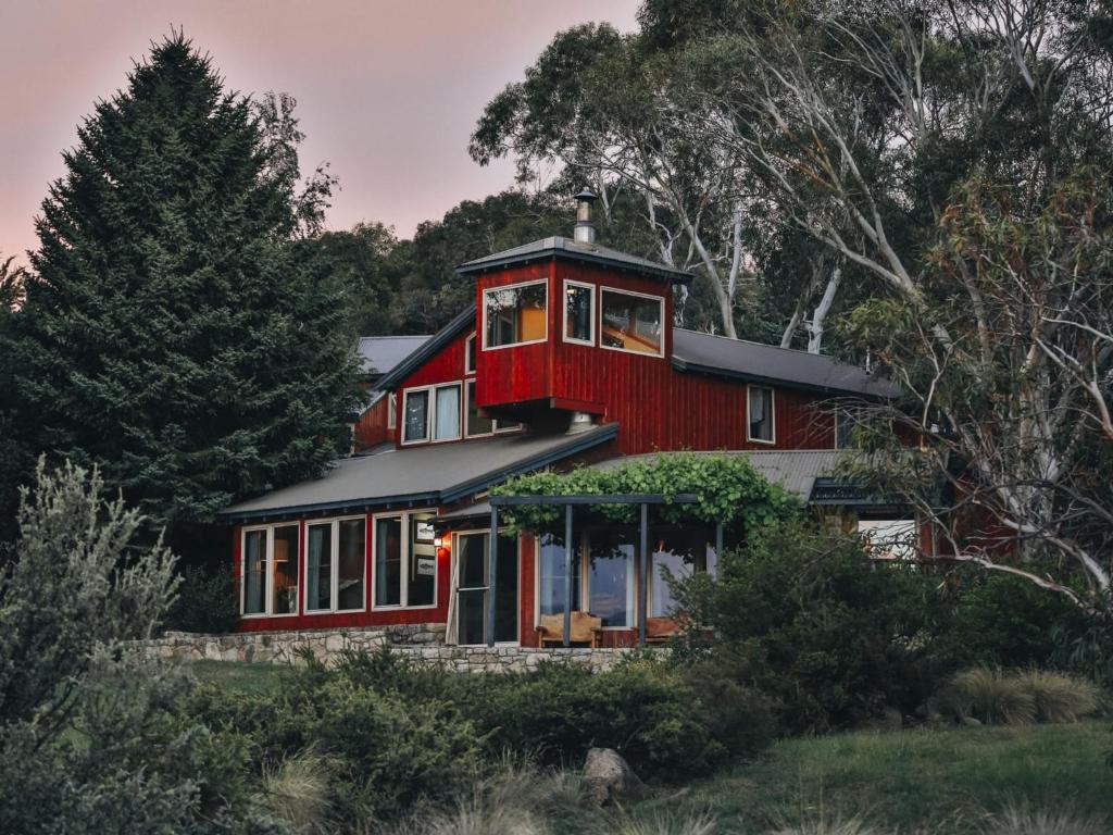 ein rotes Haus mit einer umlaufenden Veranda in der Unterkunft Edzell Stunning Waterfront Home in Jindabyne