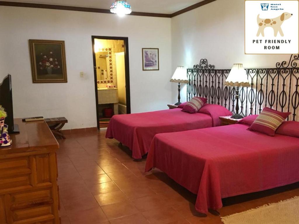 two beds in a hotel room with red sheets at San Angelo in Cuernavaca