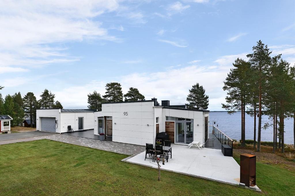 una casa blanca con un gran patio trasero y el agua en Luxury modern 5BR beach House for Weekend Getaways near Piteå en Piteå