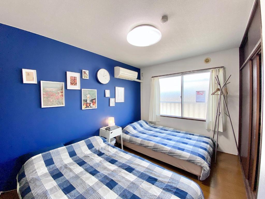 two beds in a room with a blue wall at 松戸駅ｽｸﾞ 1DK 出張に旅行に Nomad松戸宿019 in Matsudo