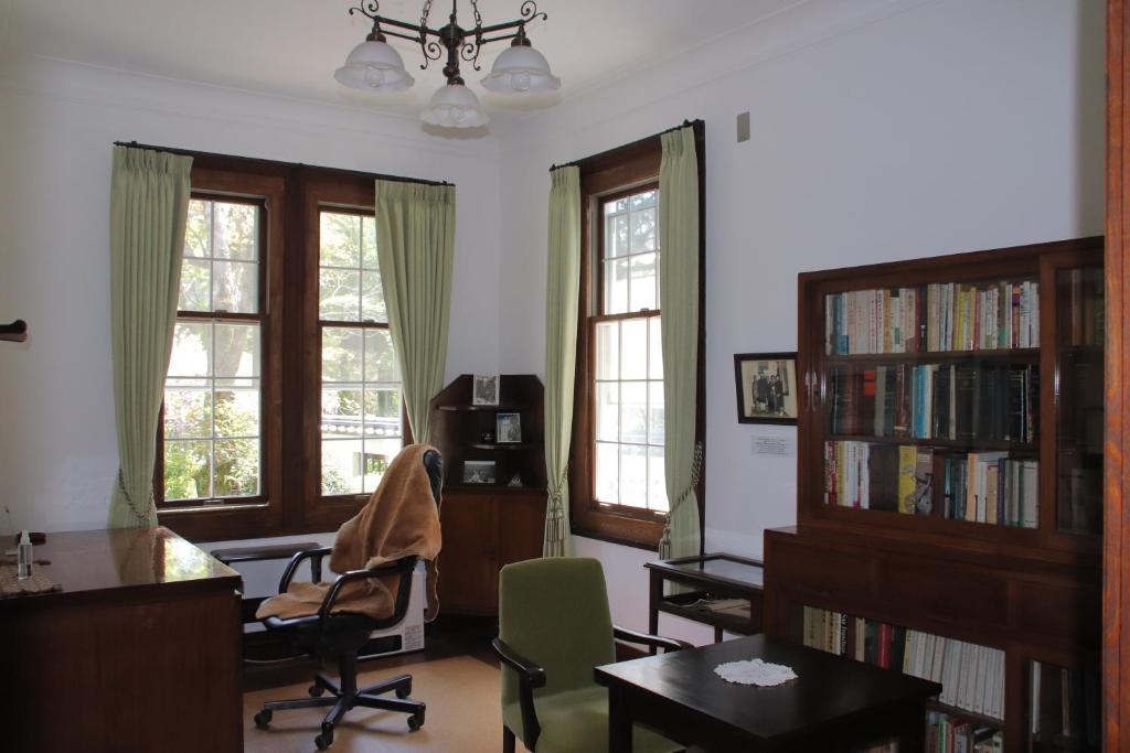 a living room with a desk and chairs and windows at Yamaguchi House,Historic Private House with Open-Air Hot springs in Hakone