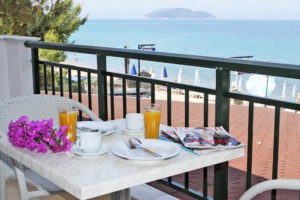 a table with food and drinks on a balcony with the beach at Miramare Hotel in Neos Marmaras