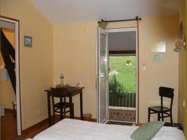 a bedroom with a bed and a table and a window at Auberge Les Tonnelles in Saint-Léonard