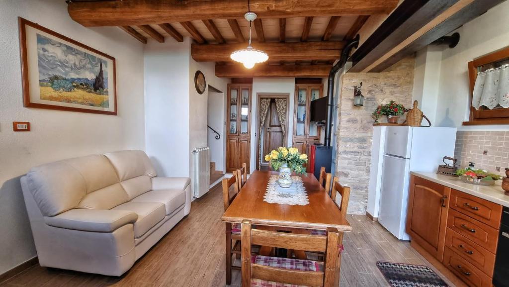 cocina y sala de estar con mesa y sofá en La casa della maestra località San Giovanni Spello, en Spello