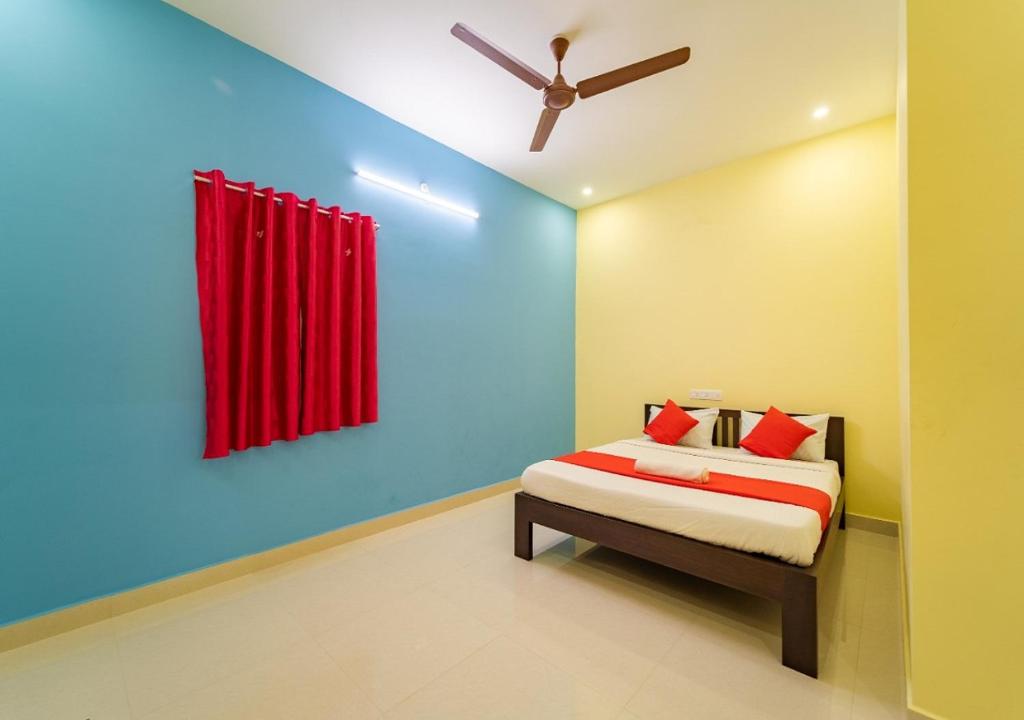 Aashikha Farm House في بونديتْشيري: غرفة نوم بسرير وستارة حمراء