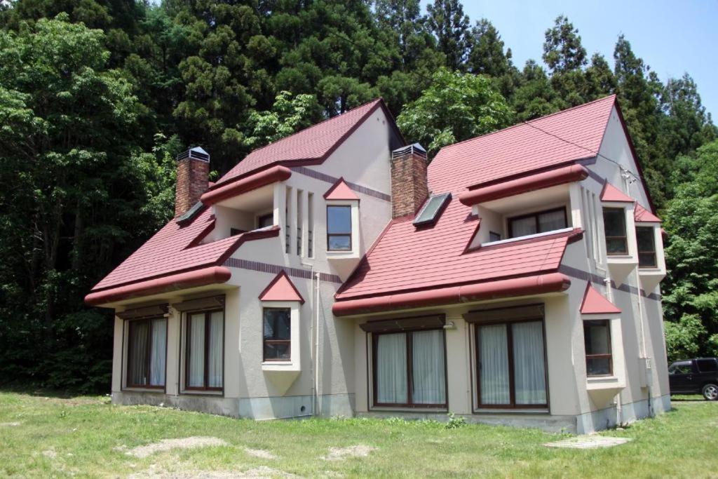 een huis met een rood dak op een veld bij Cottage Hotel Fenice Hakuba in Hakuba