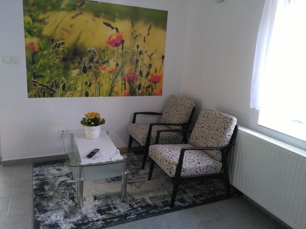 two chairs and a table in a room with a painting at Apartmán GUTINO in Česká Třebová