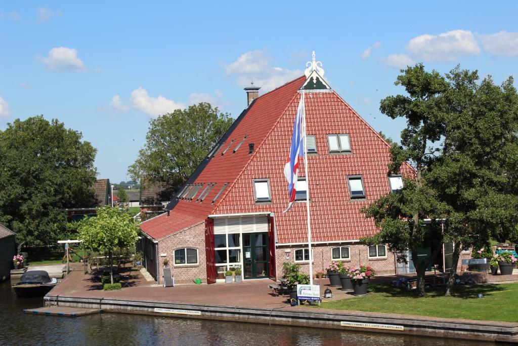 un edificio con techo rojo con una bandera. en Wartena Hoeve - Vega B&B, en Warten
