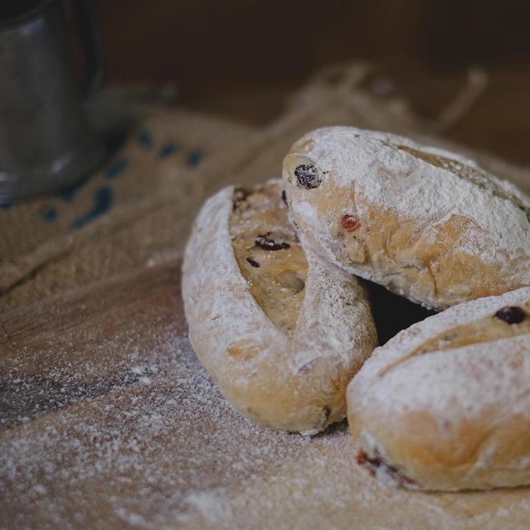 A close-up of powdered fruit-studded bagels arranged on a wooden serving surface.