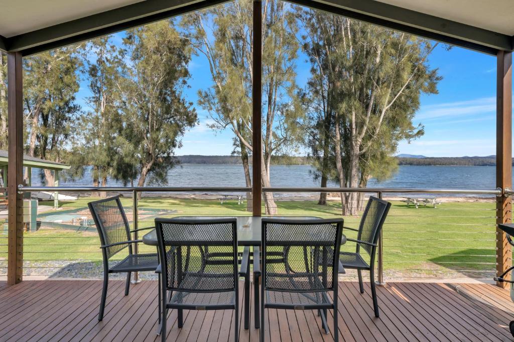 a table and chairs on a deck with a view of the water at Ingenia Holidays Ocean Lake in Bermagui