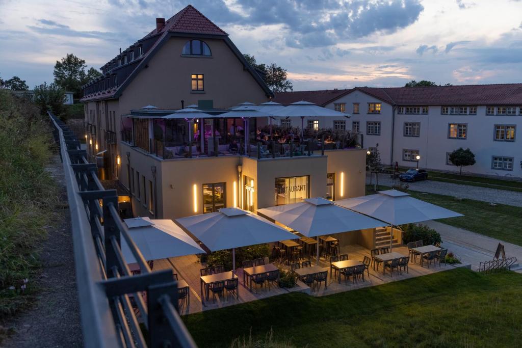 eine Luftansicht eines Gebäudes mit Tischen und Sonnenschirmen in der Unterkunft DAS KEHRS - Hotel auf dem Petersberg in Erfurt