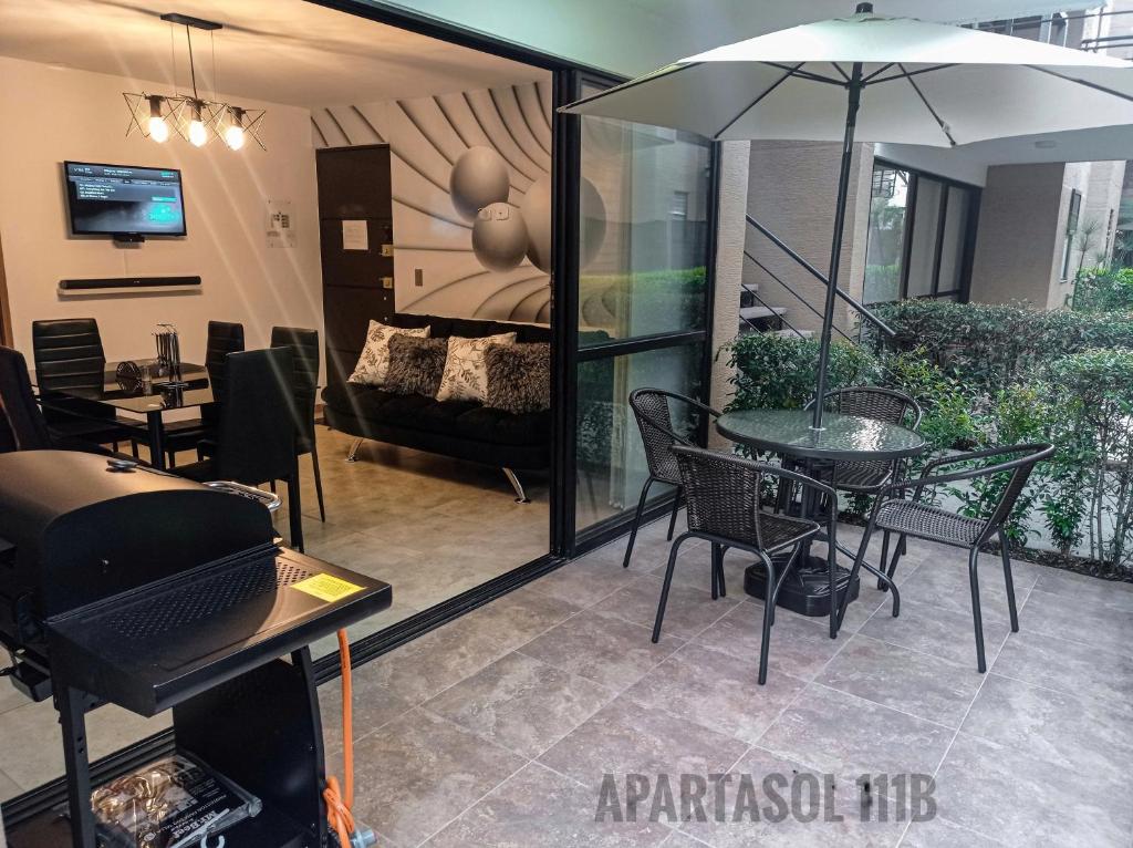 eine Terrasse mit einem Tisch, Stühlen und einem Sonnenschirm in der Unterkunft Apartasol, Eje cafetero Reservas de la Colina 111B in La Tebaida
