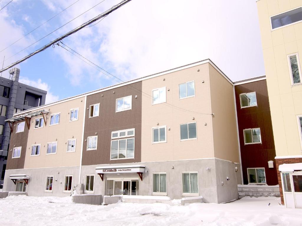 an apartment building with snow in front of it at Lodge Koropokkuru in Kutchan