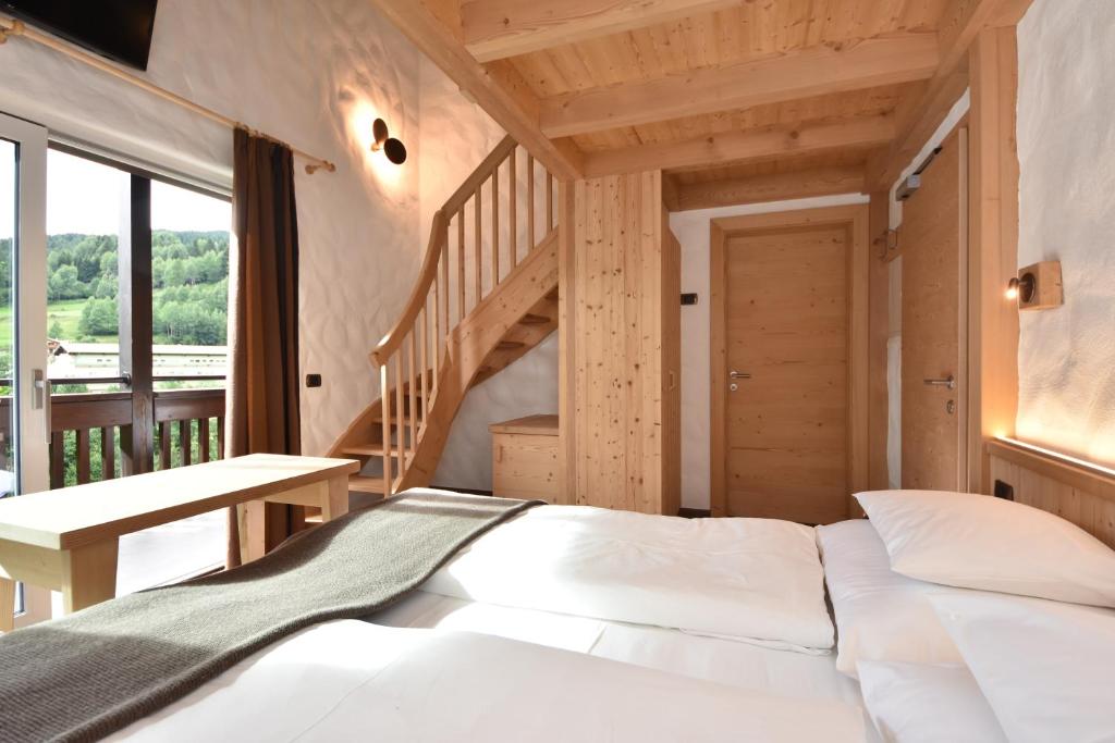 a bedroom with a white bed and a staircase at Belvedere Dolomites Flower Hotel in Moena