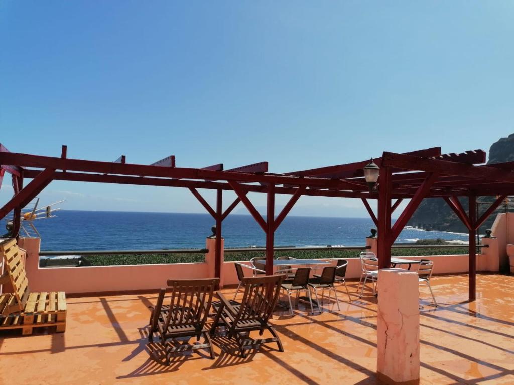 um pátio com cadeiras e mesas e vista para o oceano em Apartamentos Playa em Hermigua