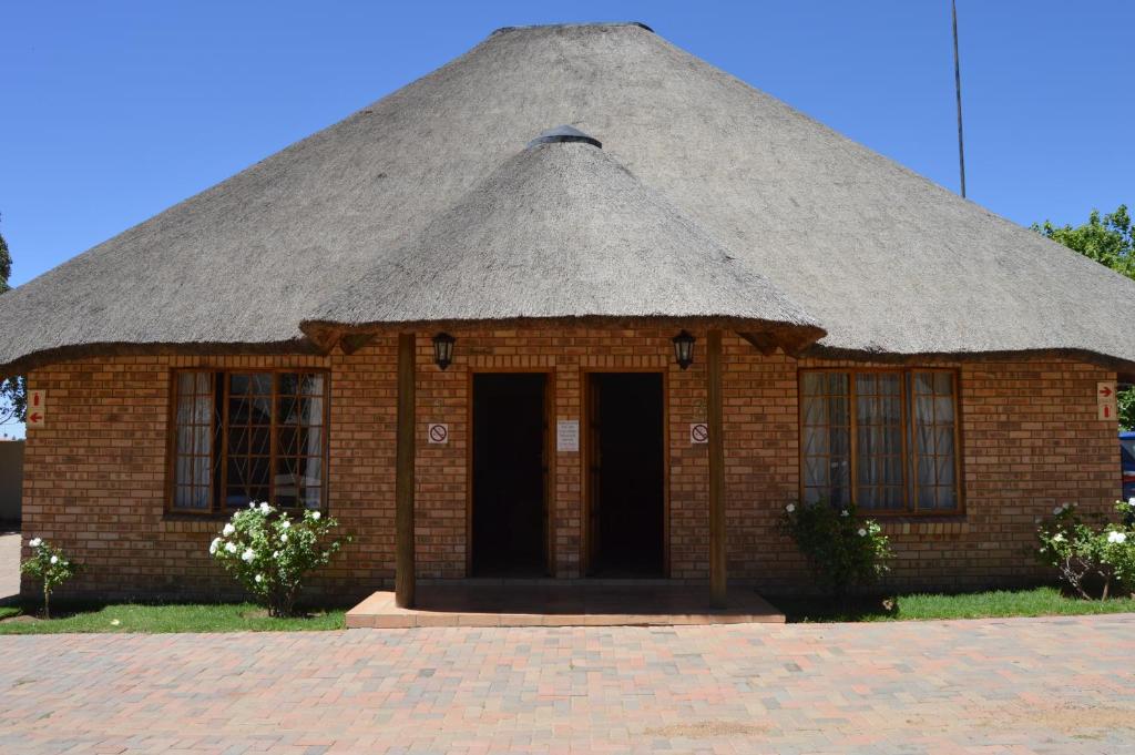 un edificio de ladrillo con techo de paja en Jarina Guesthouse, en Wolmaranstad