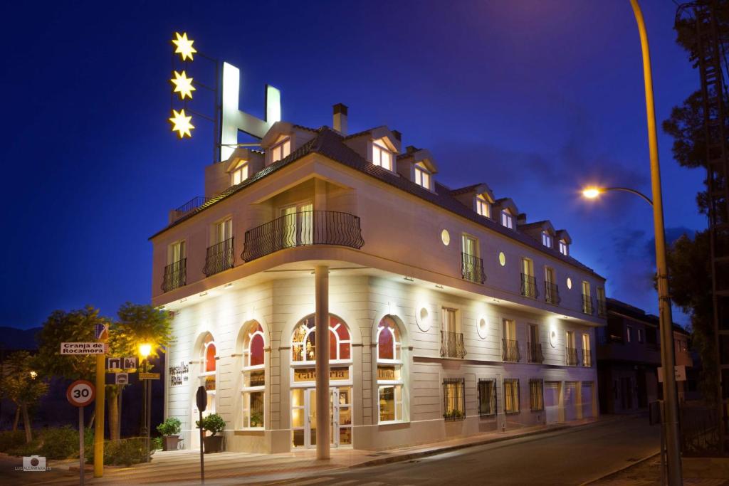 un bâtiment avec des étoiles au-dessus de celui-ci la nuit dans l'établissement Hotel Versalles, à Granja de Rocamora
