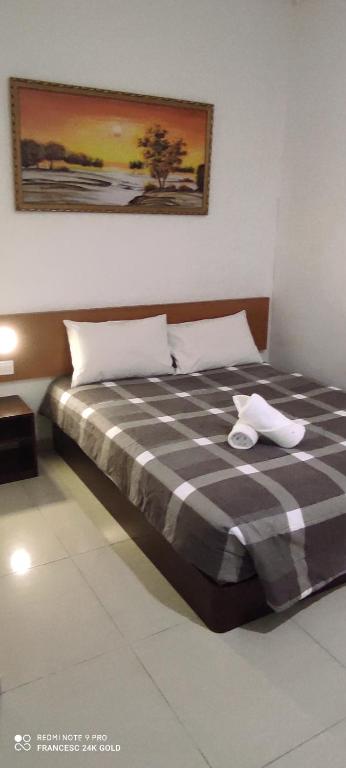 a bedroom with a bed with a checkered blanket at Aloha Hotel in Lumut