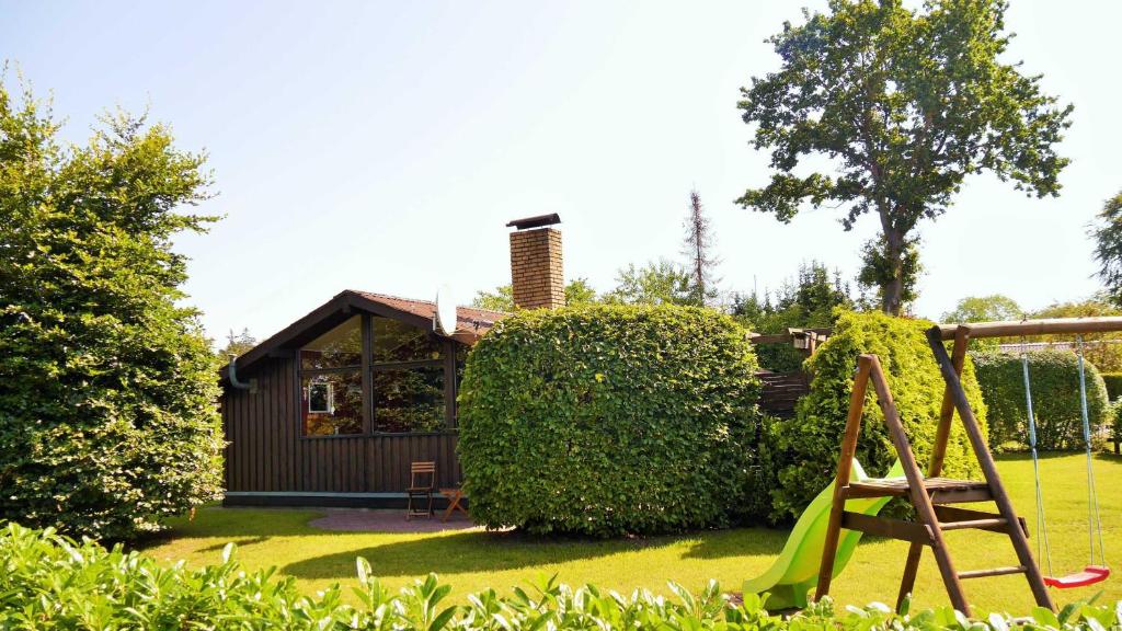 a garden with a playground and a house at Stolley - Ferienhaus mit Garten, Kamin und Sauna in Silberstedt