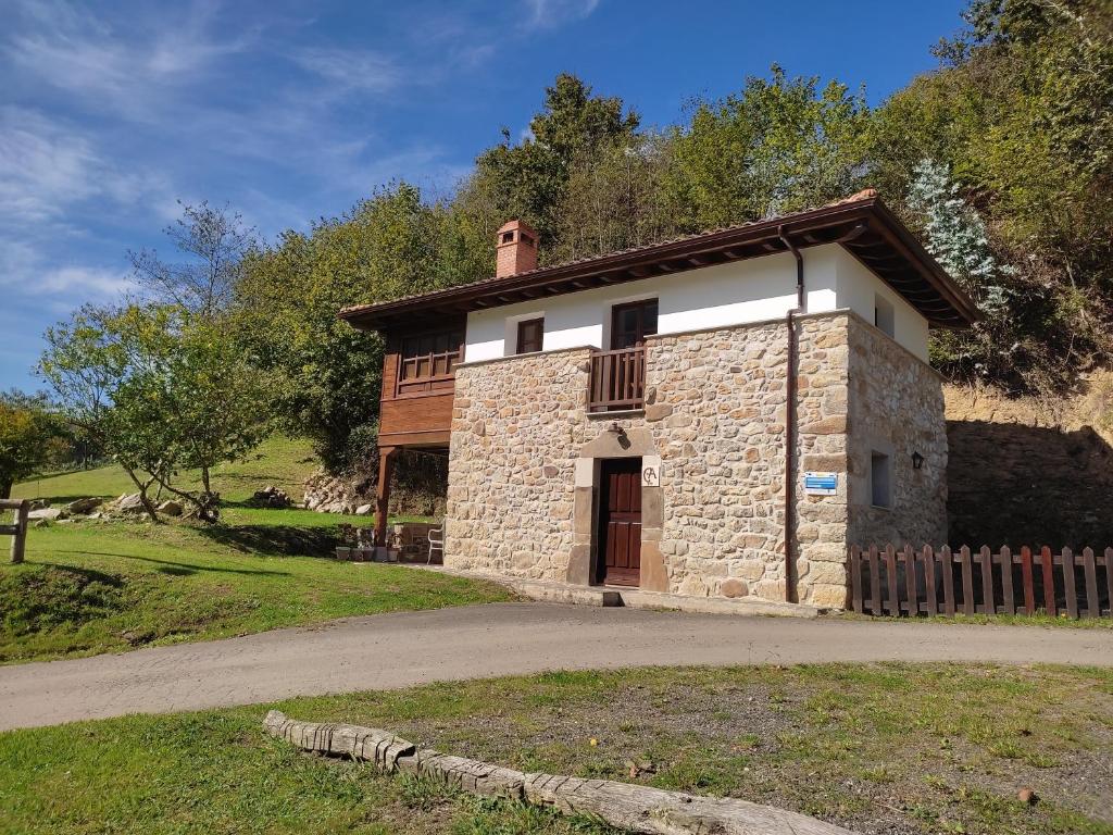 a small stone house with a fence in front of it at El Molín de La Vega Agroturismo in Ribadesella