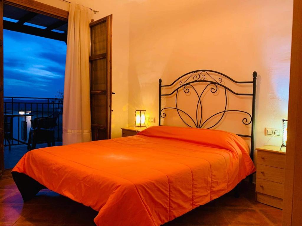 a bedroom with a bed with an orange bedspread at Apartamento Los Laureles in Laroles