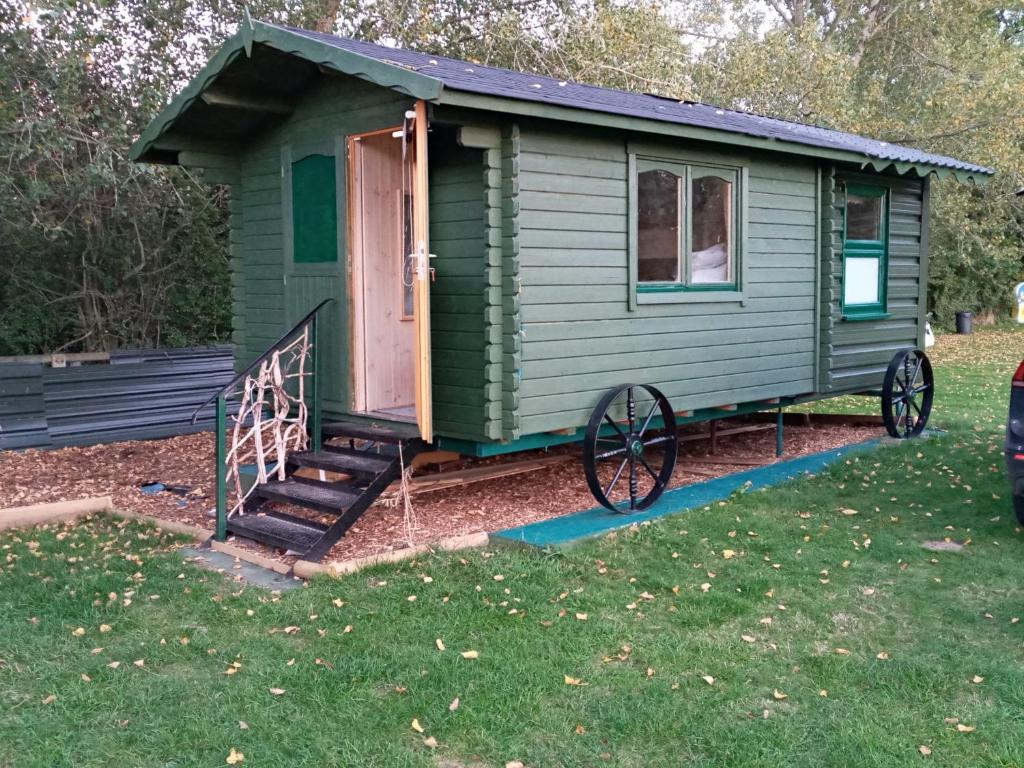 a green tiny house with a porch and a staircase at Cabin Dan in Great Malvern