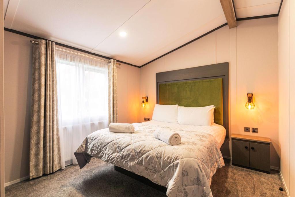 een slaapkamer met een bed en een groot raam bij Bushmills Lodge with Hot Tub in Thornton