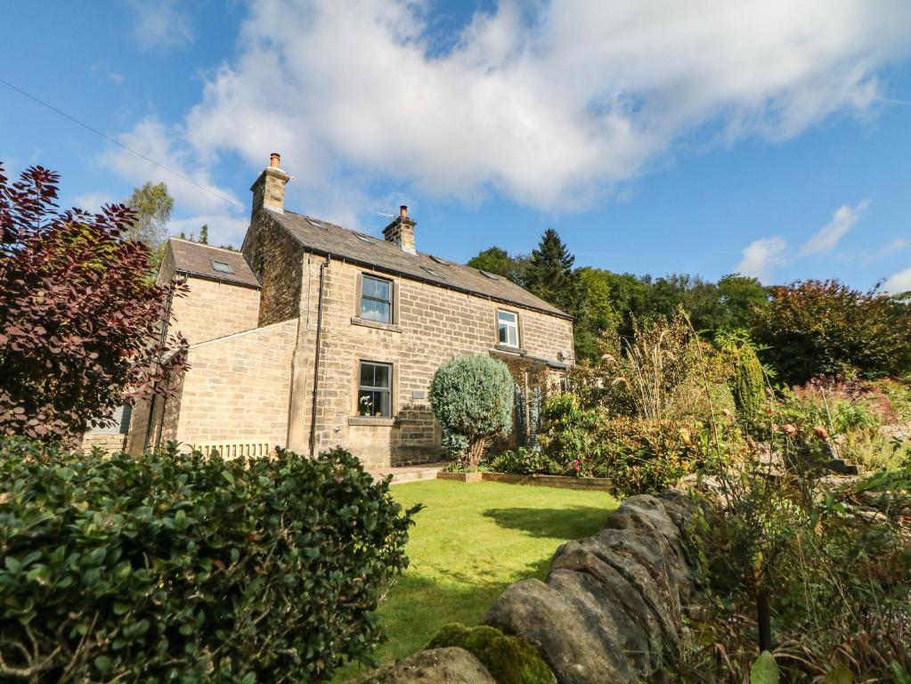 an old stone house with a garden in front of it at 1 Orchard View in Hathersage