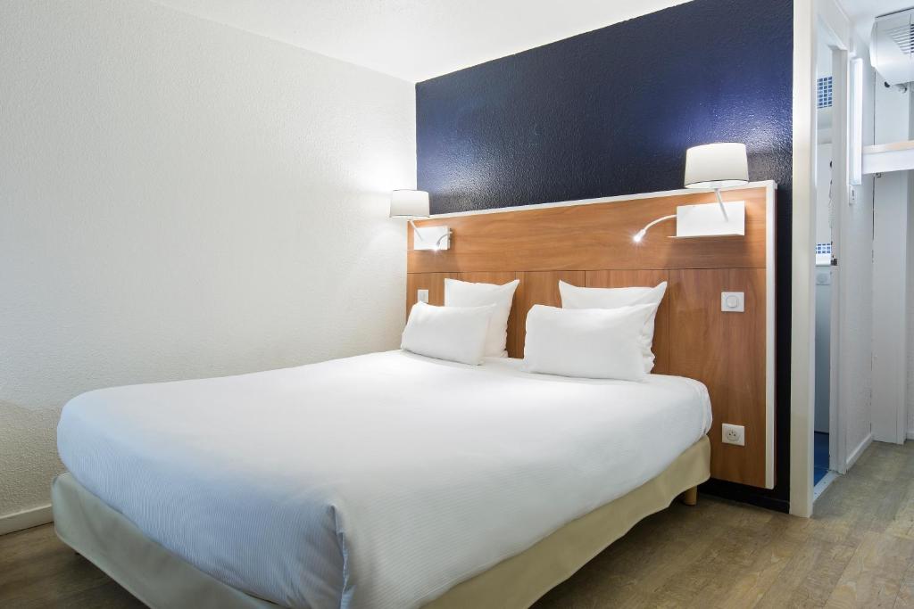 a bedroom with a large bed with white pillows at Comfort Hotel ORLY-RUNGIS in Rungis