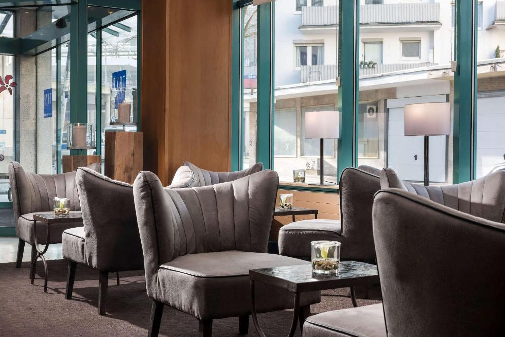 a waiting room with chairs and tables and windows at TRYP by Wyndham Köln City Centre in Cologne