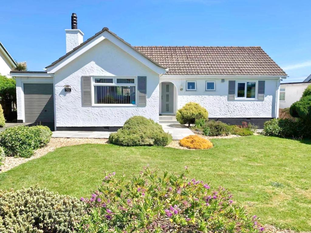 a small white house with a grass yard at Bungalow33 Benllech in Benllech