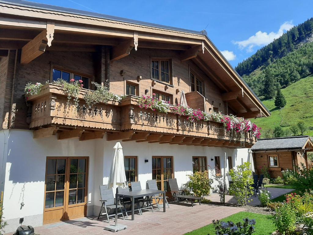 a house with a balcony with a table and chairs at Hochalmbahnen Chalets Rauris 1-06WE4, Maislaufeldweg 1g OG in Rauris