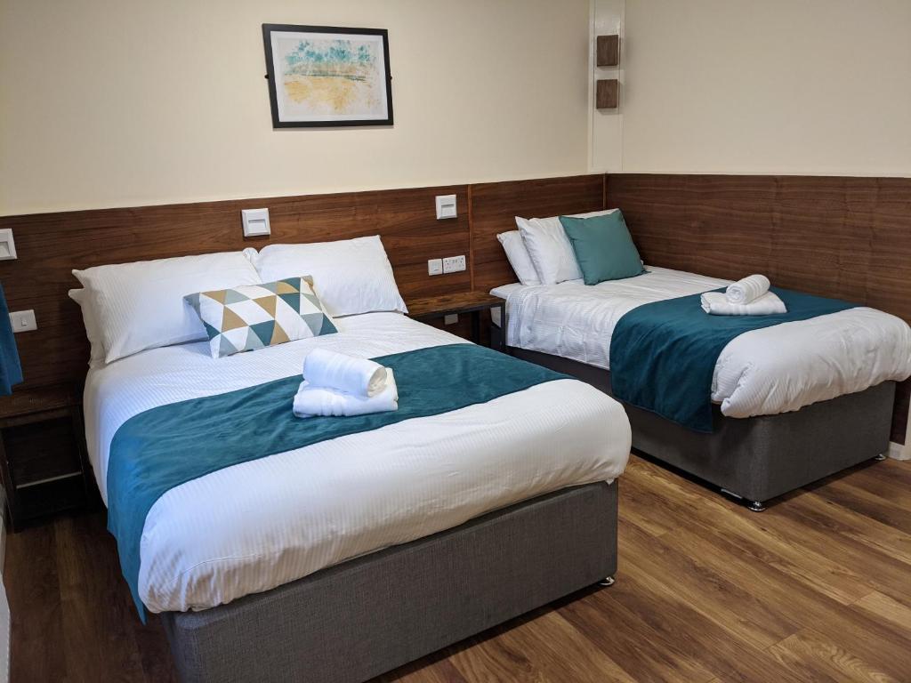 a hotel room with two beds and two nightstands at Hazeldean in Manchester
